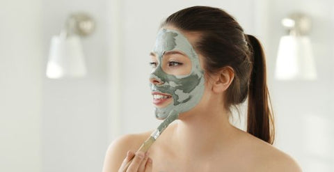 Femme avec masque visage argile verte